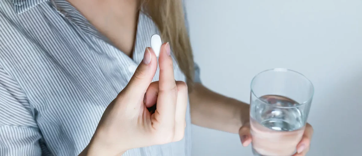 67b84e6d88d0bb650525d39c_HEADER_woman-holding-pill-glass-water